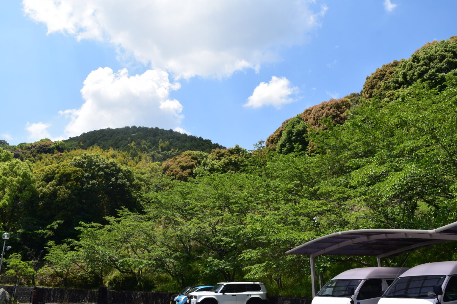 施設周辺の緑豊かな山々と駐車場。自然に囲まれた立地環境