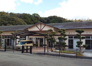 日本の介護施設の建物外観。平屋造りで和風デザイン、駐車場を備えている。