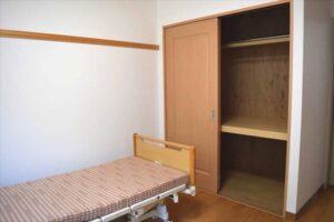 木製ベッドと収納クローゼットを備えた介護施設の個室